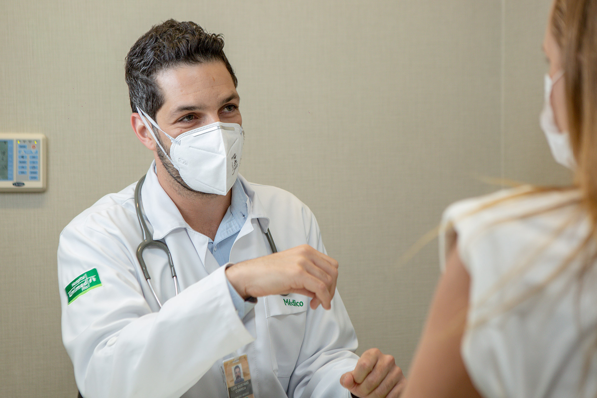 Foro de médico branco com cabelo curto, preto de mascara atendendo paciente