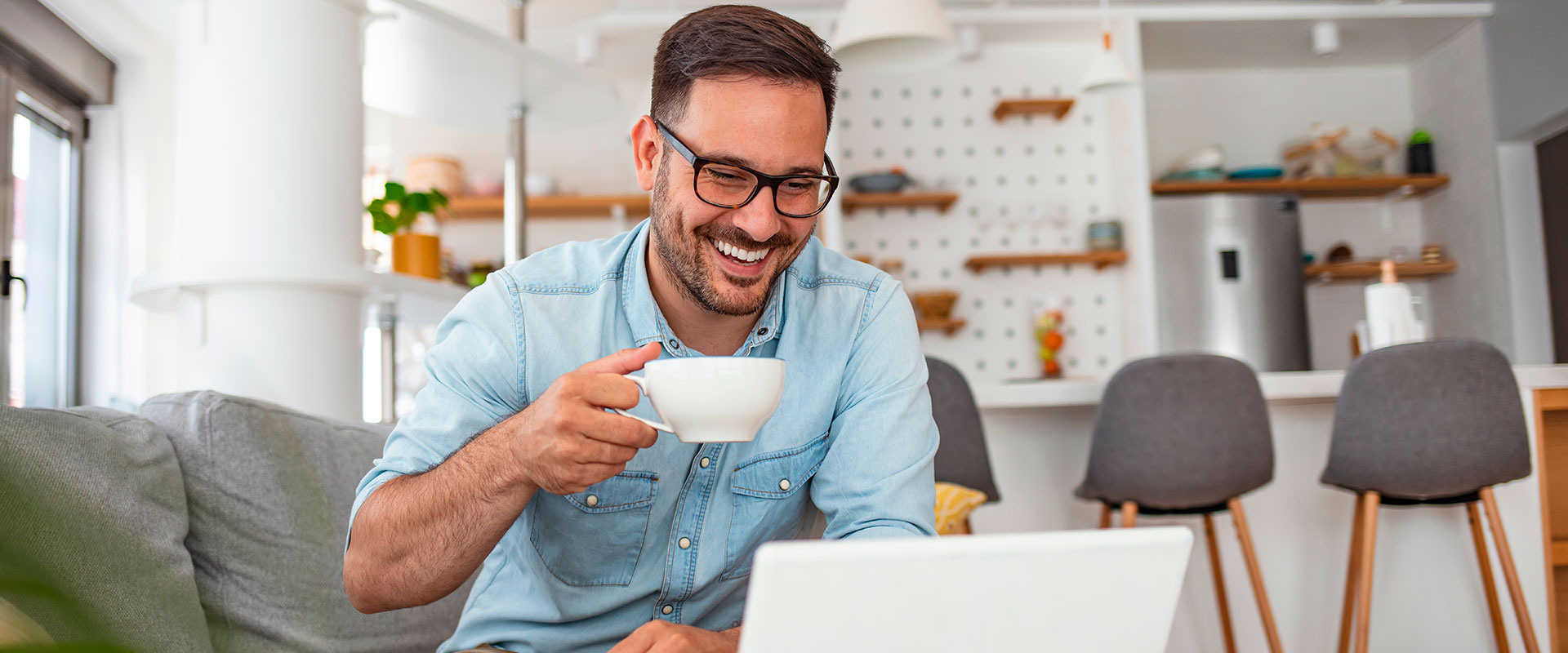 homem de oculos tomando café e mexendo no computador