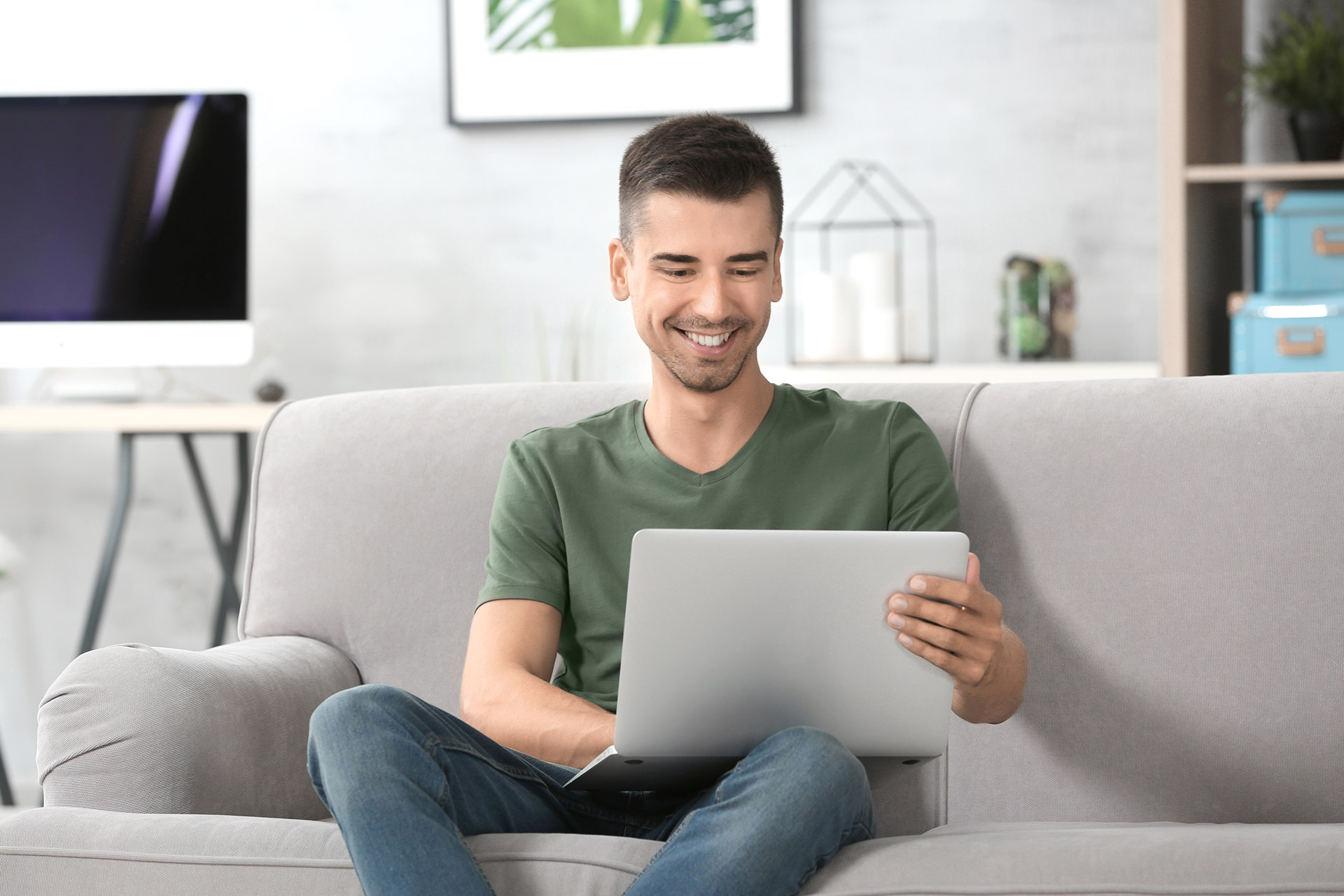 Homem sentado no sofá usando o laptop no colo