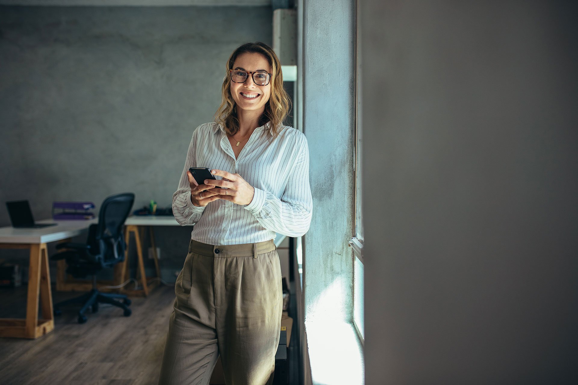 Imagem de mulher sorrindo com celular na mão